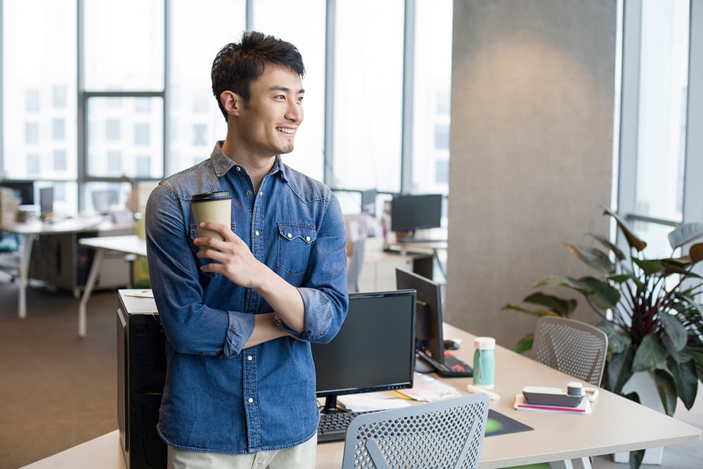 Un homme vêtu d'une chemise en jean se tient debout dans un bureau moderne