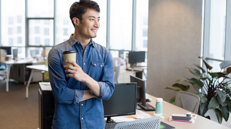 Un homme vêtu d'une chemise en jean se tient debout dans un bureau moderne