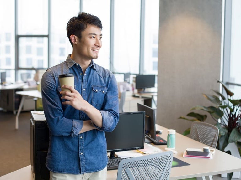 Un homme vêtu d'une chemise en jean se tient debout dans un bureau moderne